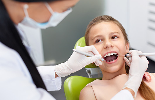 Dentist performing dental exam for young girl