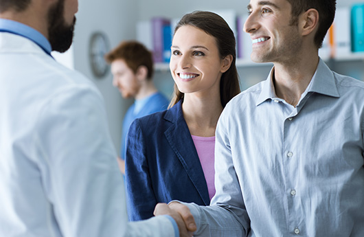 Man and woman smiling and shaking hands with dentist