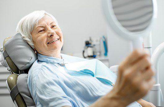 Older woman looking at smile after full mouth reconstruction