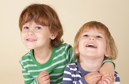 Two young boys smiling after dental sealant placement