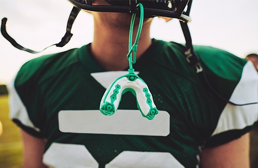 Green sports mouthguard hanging from football helmet