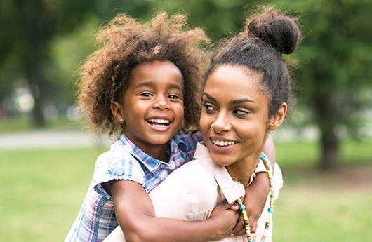 Mother giving her daughter a piggy back ride after silver diamine fluoride treatment