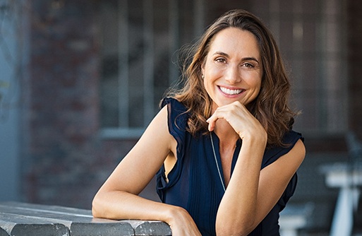 a smiling person resting their arm on a park table