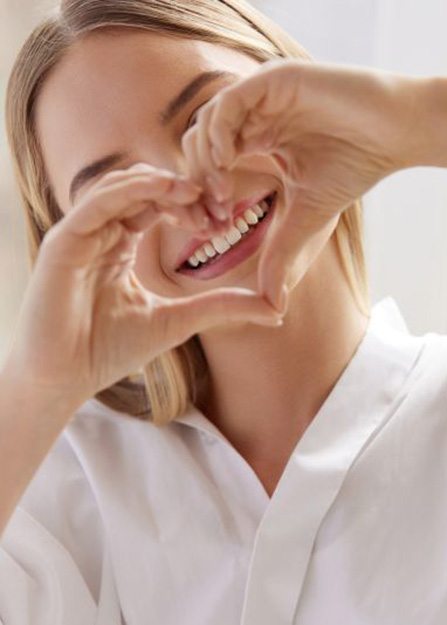 Woman using her hands to make a heart shape around her teeth