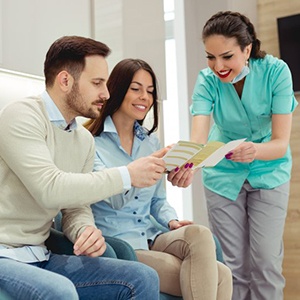 dental team member showing a pamphlet to two patients 