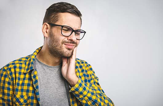 Man with a dental emergency in Lebanon holding his cheek