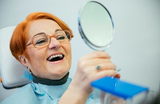 A woman looking at her smile in the mirror