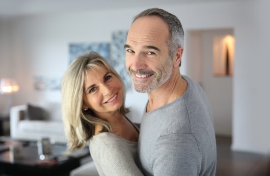 Man and woman smiling together after dental implant tooth replacement