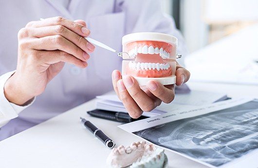 Dentist holding smile model while discussing dental treatment plan