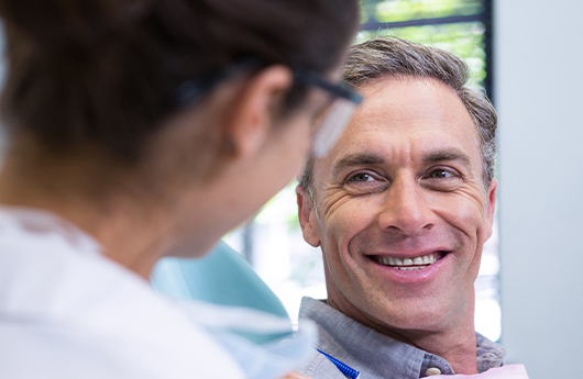 Man in dental chair smiling at dentist