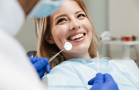 Woman in dental chair smiling at dentist