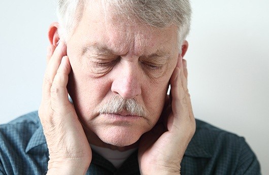 Man in need of tooth replacement holding jaw in pain