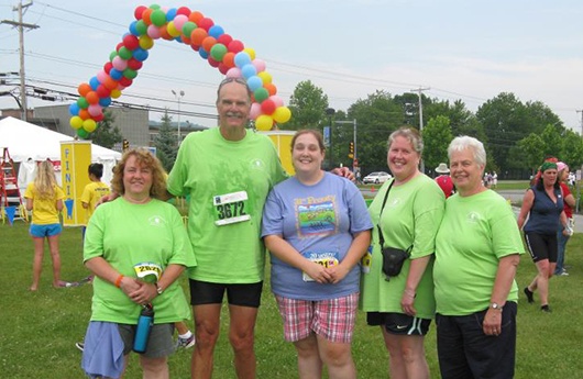 Four dental team members and patient smiling together at event