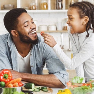 child giving their father a cherry tomato