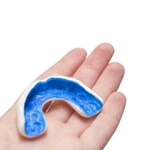 person holding blue mouthguard in their hand