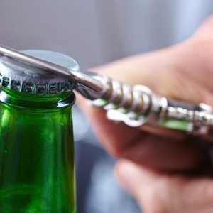 person using a bottle opener on a green bottle