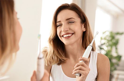 Smiling woman holding an electric toothbrush