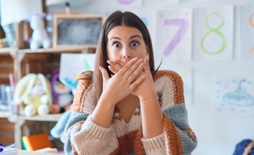 Woman covering her mouth in need of emergency dentistry