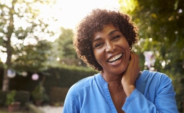 Woman with flawless smile after replacing missing teeth