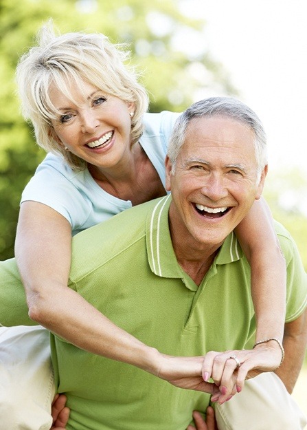 Older man and woman sharing healthy smiles after dental office visit