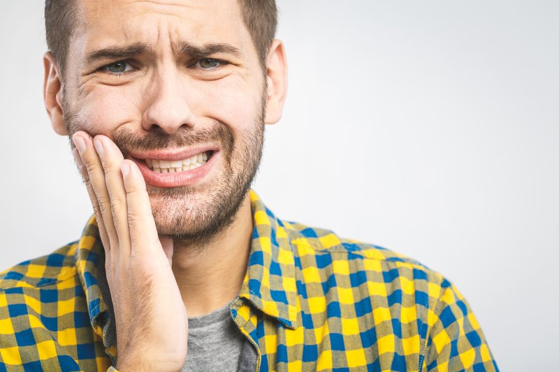 man holding cheek with tooth pain in Lebanon