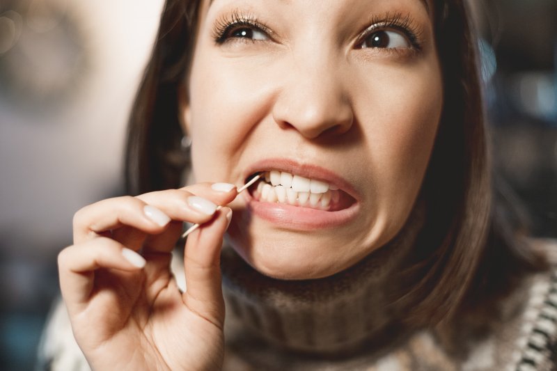 Woman trying to remove an object stuck between teeth