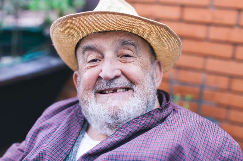 A smiling, elderly man with a missing tooth