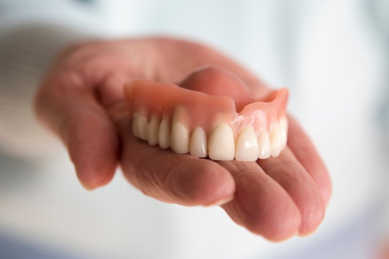 A closeup of a hand holding a removable denture